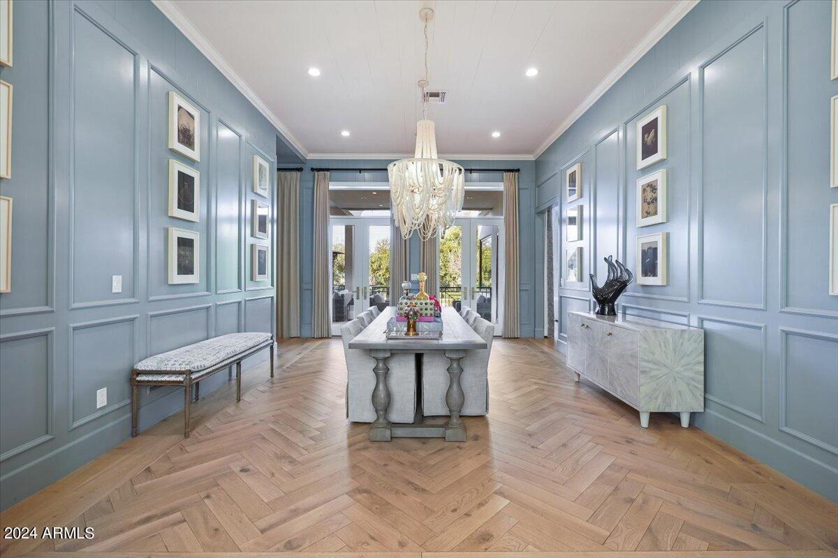 Dining room with a large table, chairs and chandelier.