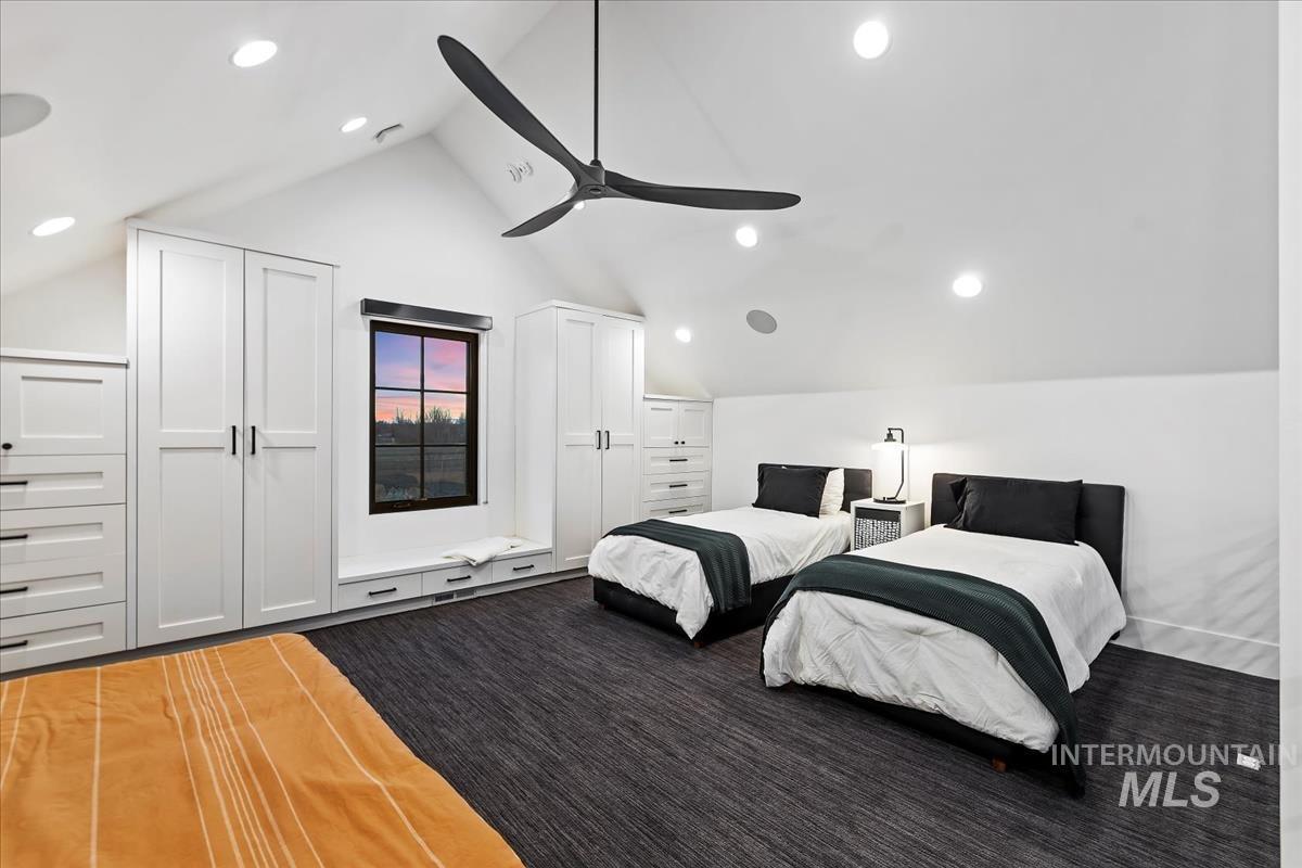 Bedroom with two beds, glass window, ceiling fan and a carpet flooring.