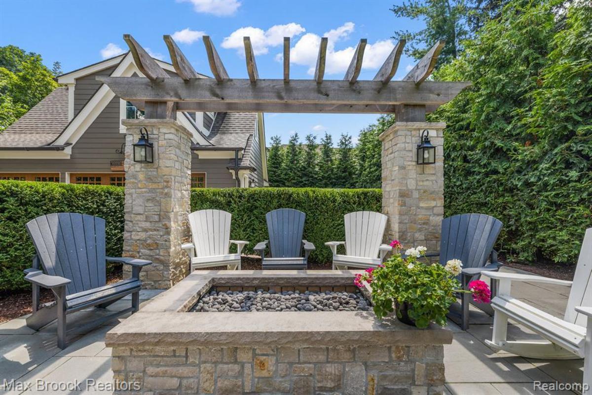 Pergola with chairs and a fire pit.