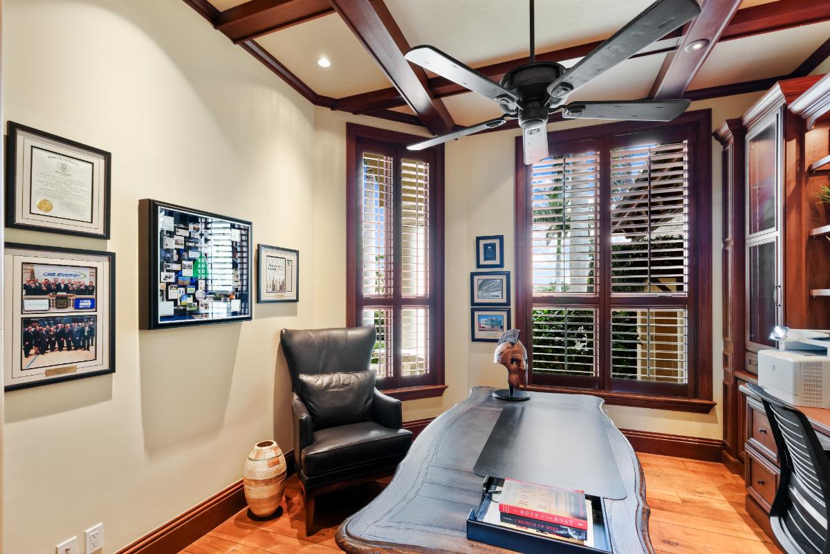 Home office with a desk, chair, glass windows and wood flooring.