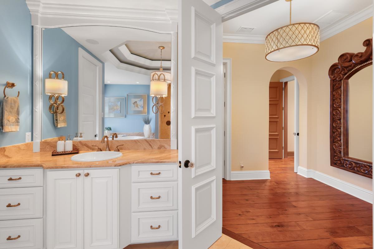 Bathroom with a sink, mirror and a wooden door.
