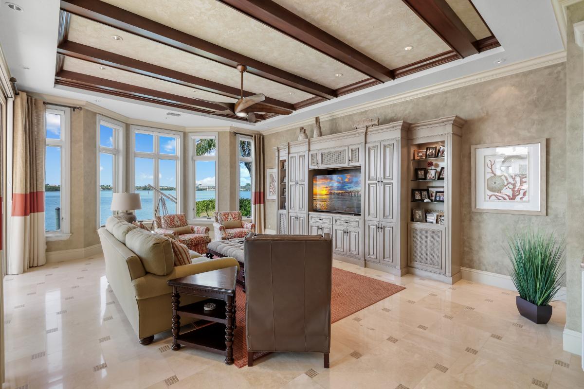 Living room with a couch, glass windows, TV and a large rug.