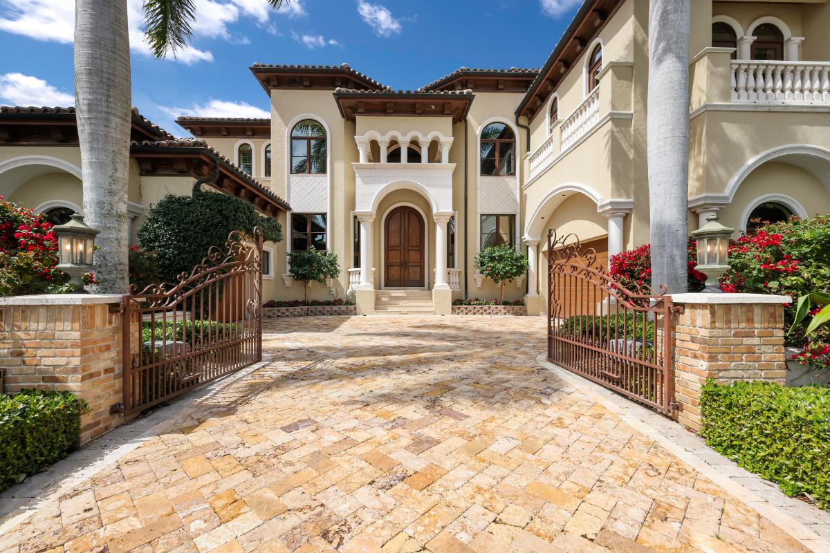 Front gate entrance of the property with a metal gate and a driveway.