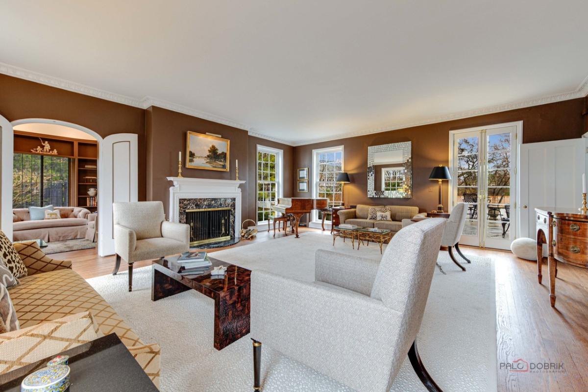 Living room with couches, chairs, glass door, fireplace and a large rug.