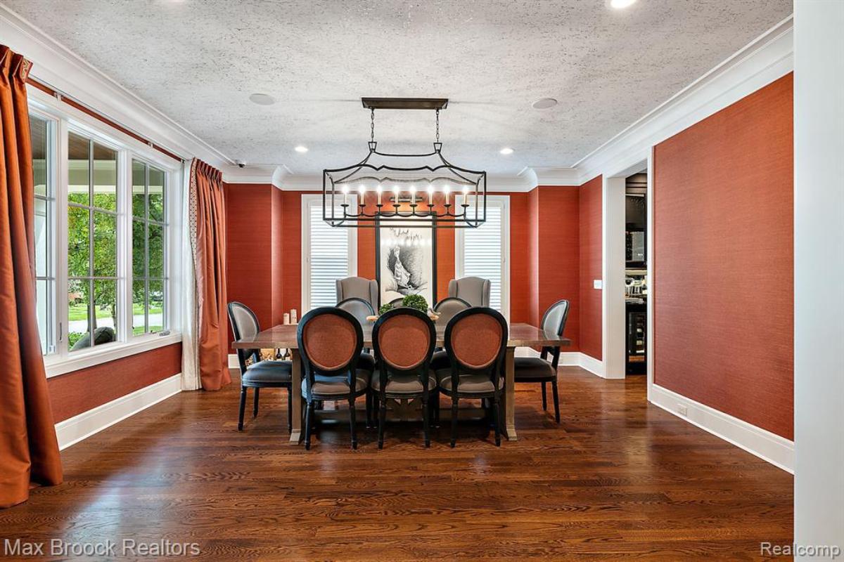 Dining room with a large table, chairs, large windows and a wooden floor.