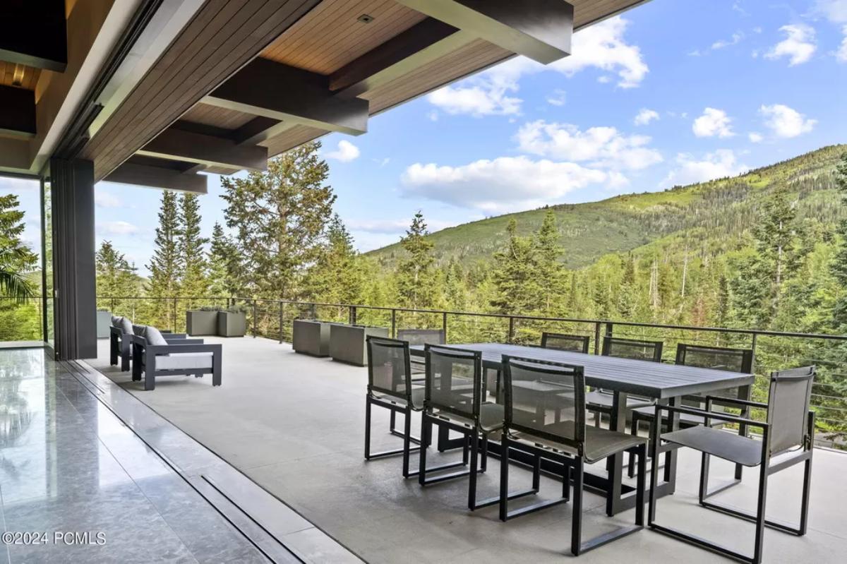 Outdoor dining area with a large table, chairs, and a view of the mountains.