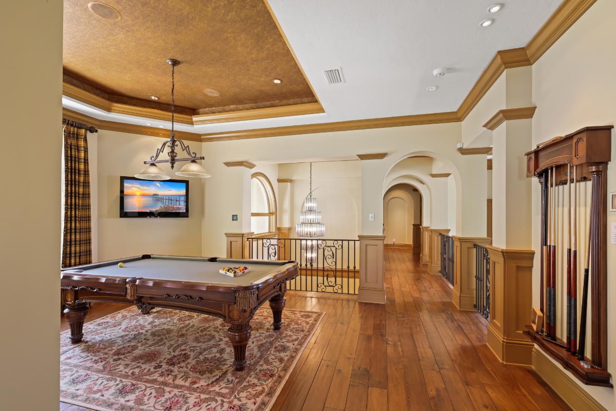 Game room with a billiard table, wooden floor and a TV.