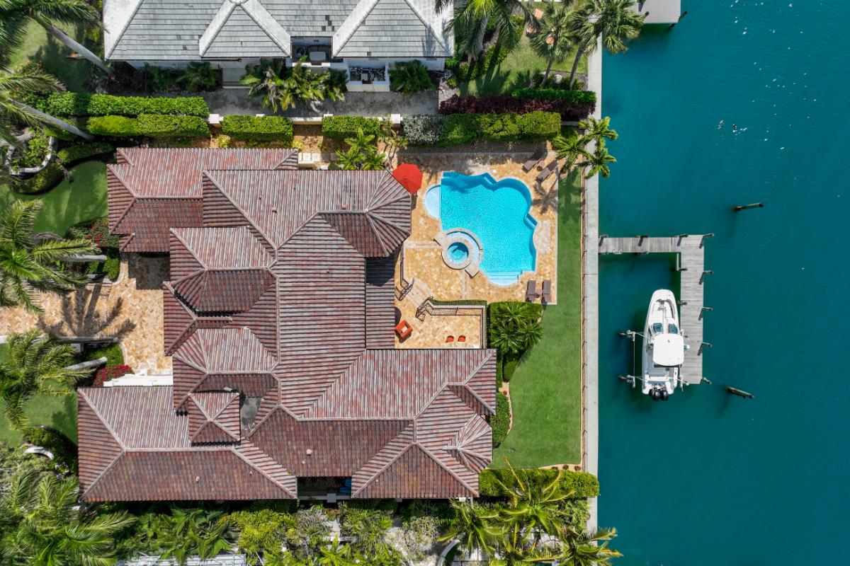 Aerial top view with a pool and a boat dock on the water.