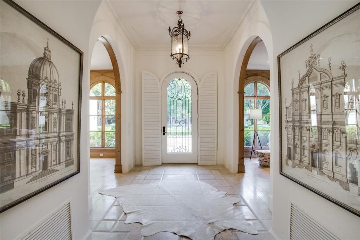 Foyer with tile flooring and paintings on the wall.
