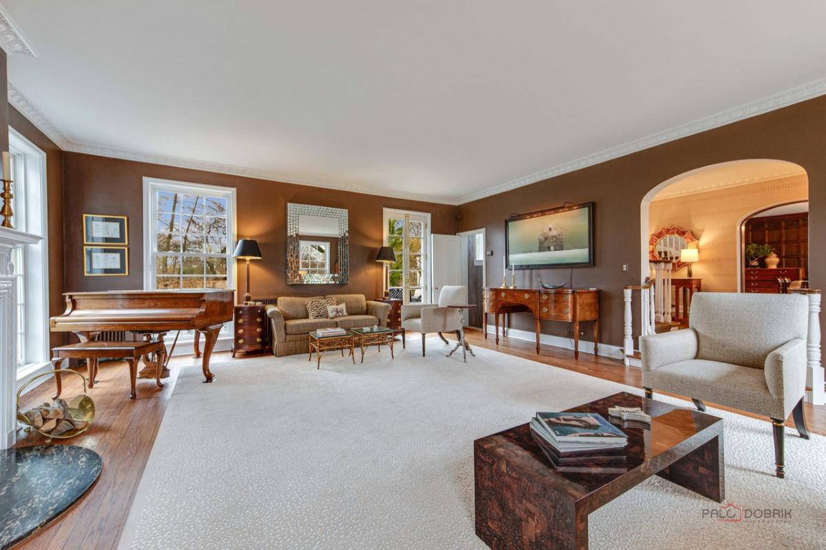 Living room with couch, chairs, glass doors, piano and a large rug.