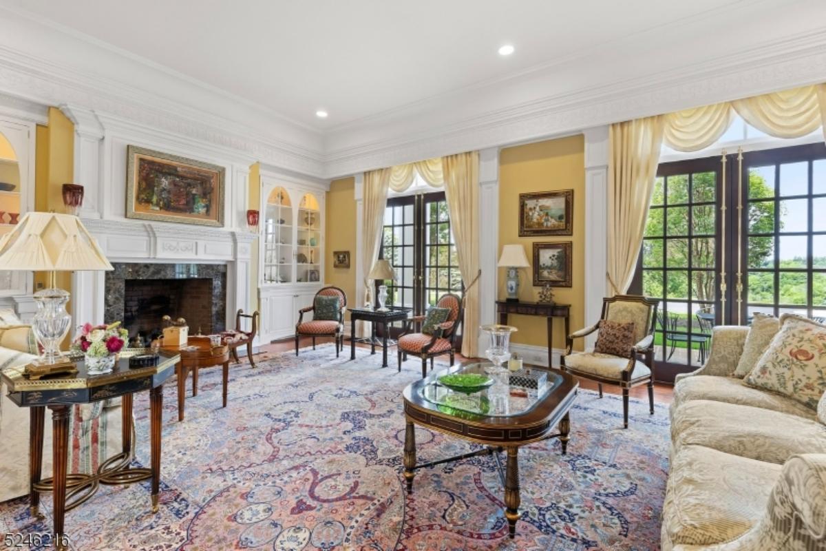 Living room with a couch, glass doors, fireplace and a large rug.
