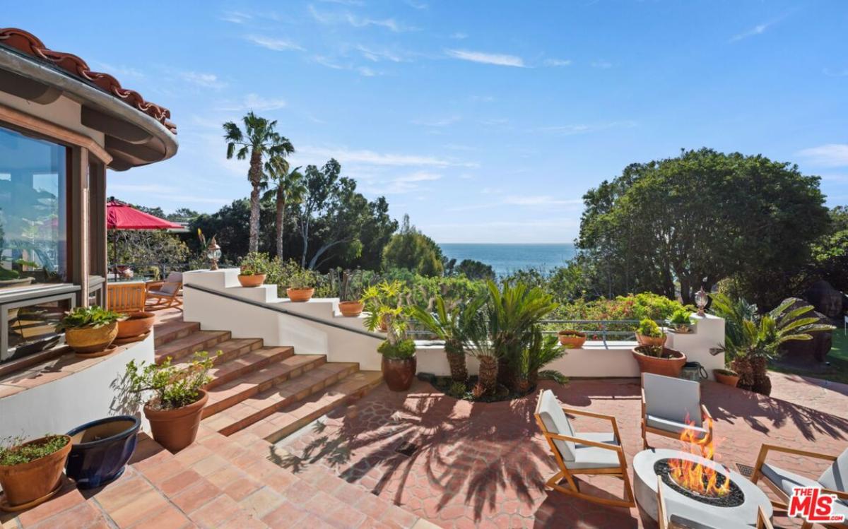 Patio with a table, chairs and a fire pit.