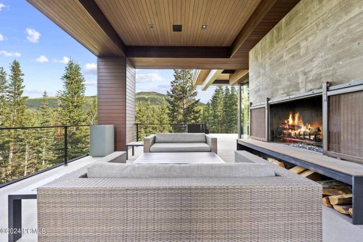 Terrace with couches, fireplace and a wooden ceiling.