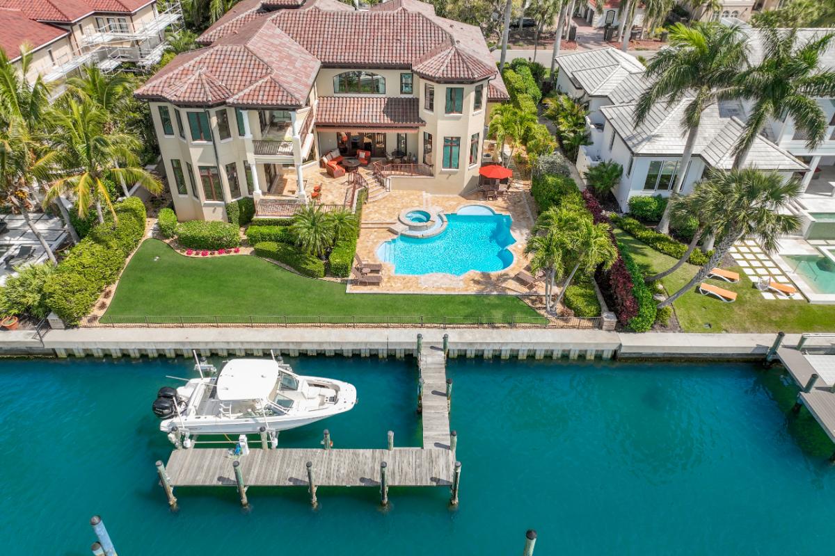 Aerial rear view of the mansion with pool and a boat dock.