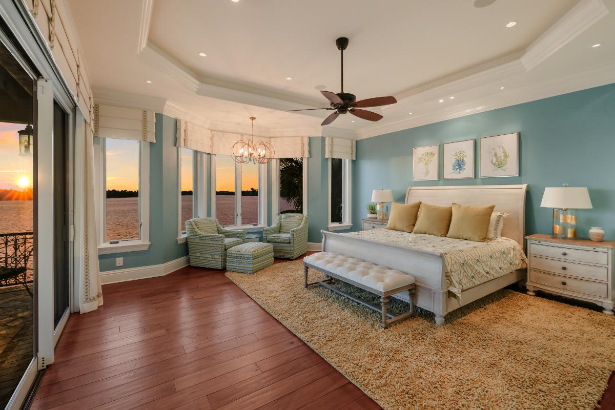 Bedroom with a large bed, large rug and large glass windows overlooking the water.