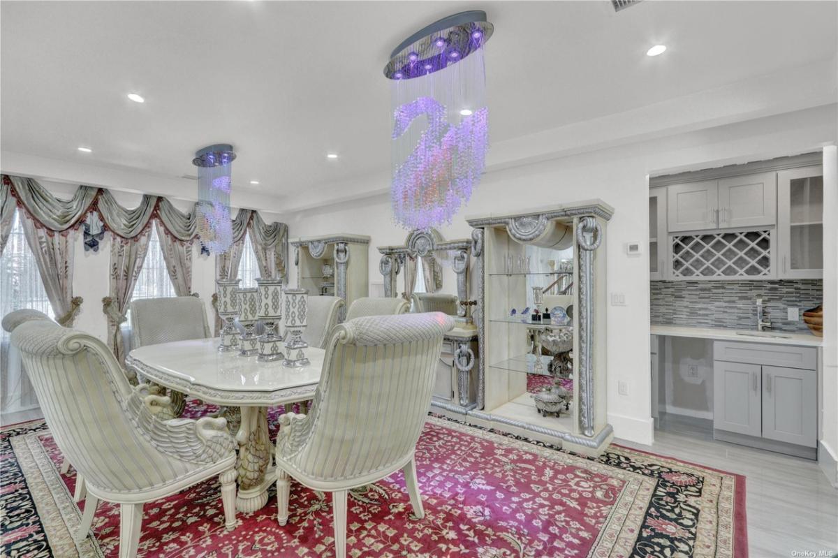 Dining room with chandeliers and a large rug.