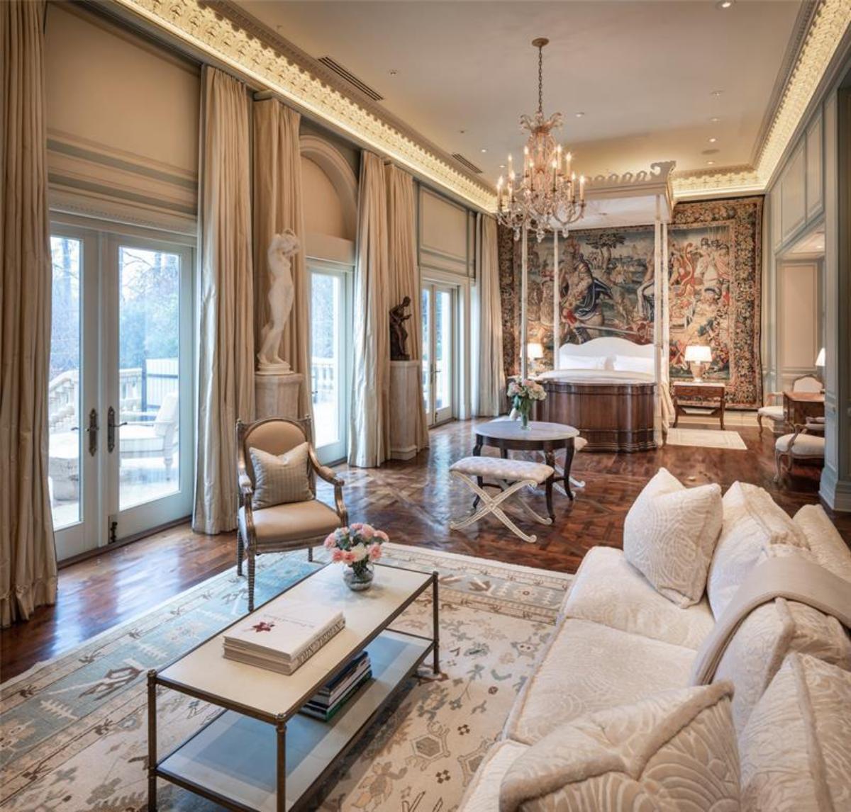 Bedroom with a large bed, chandelier, sitting area and glass doors.