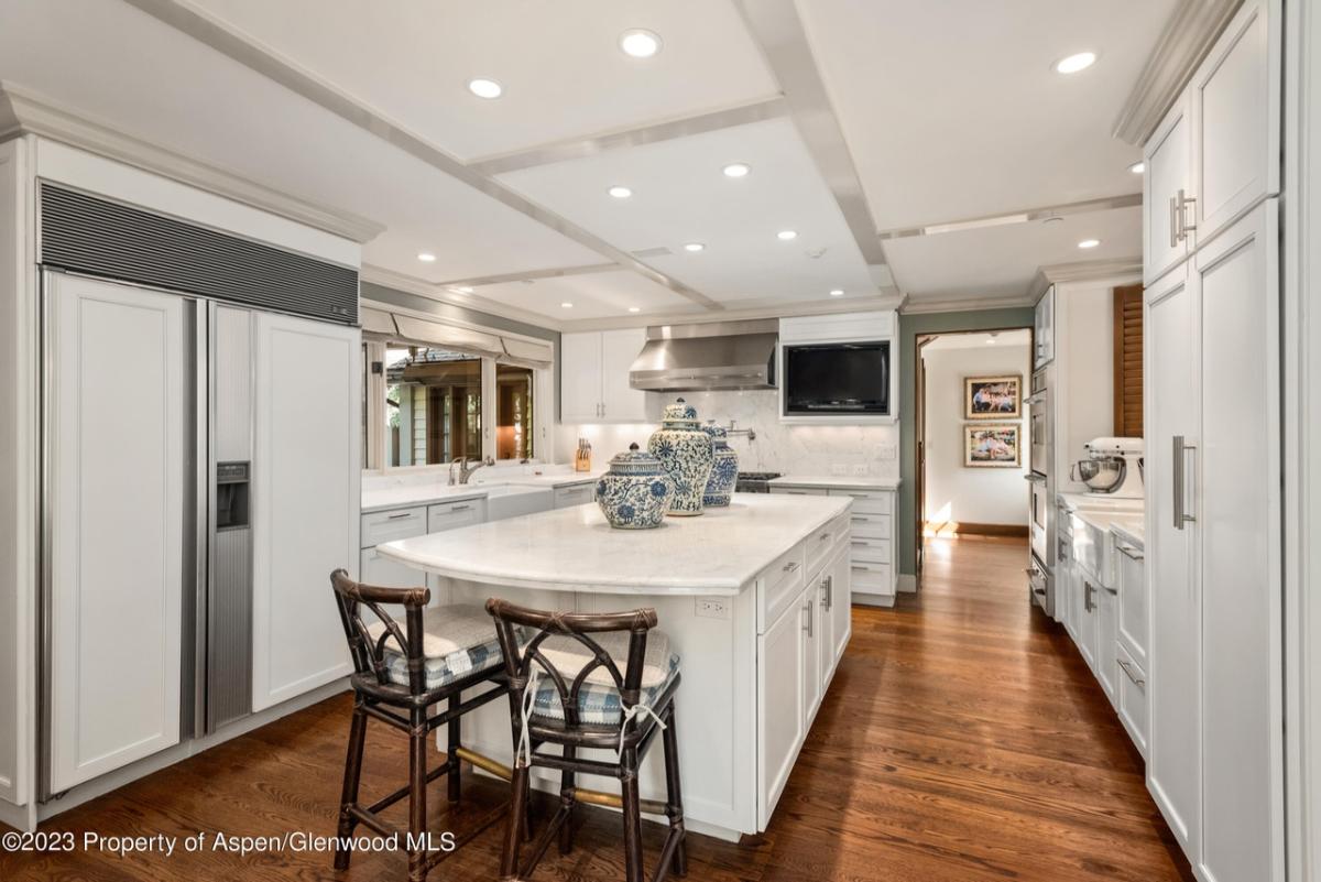 Kitchen with a large island, wood flooring, custom lights and custom cabinets.