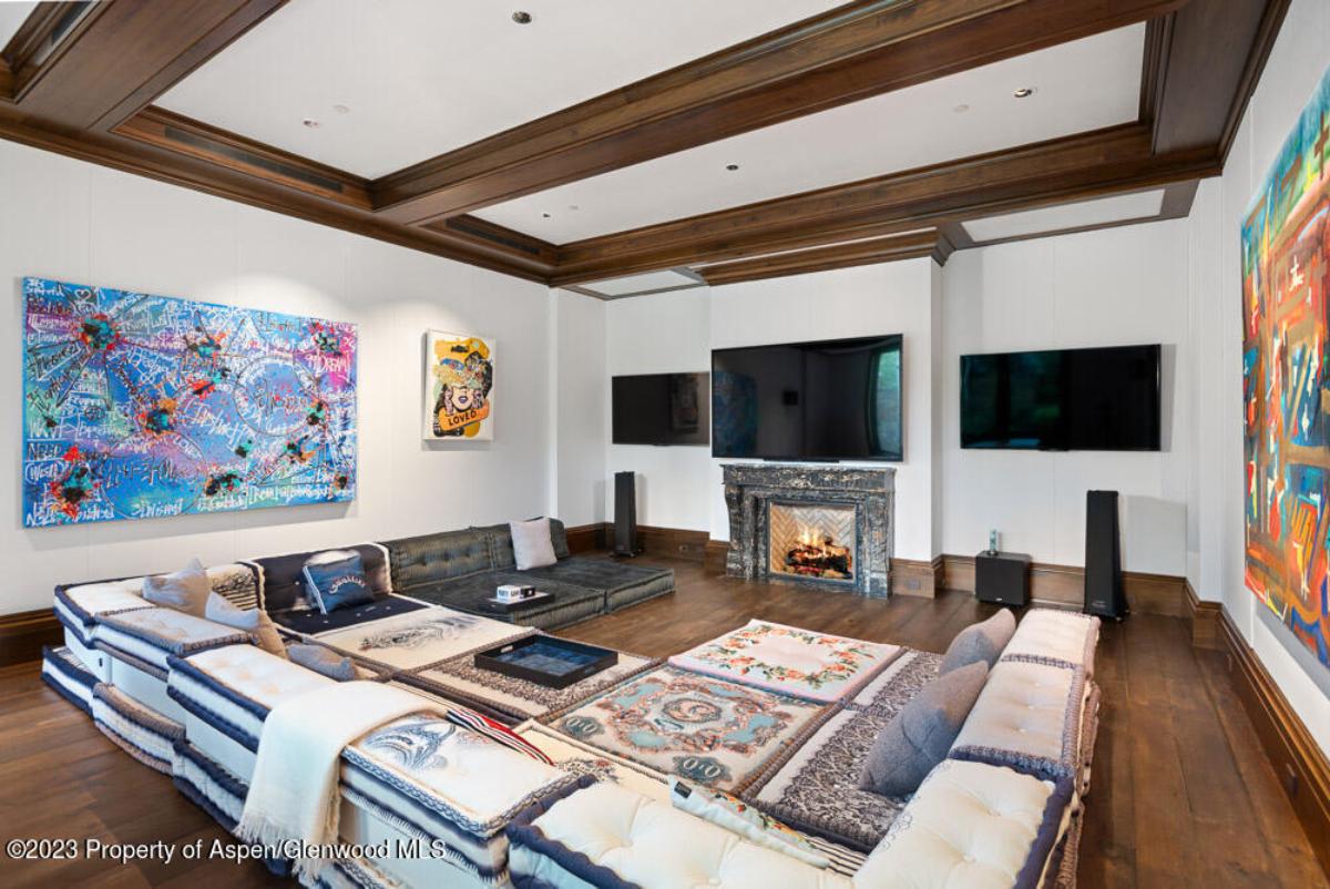 Living room with couches, TV, fireplace and a wooden floor.