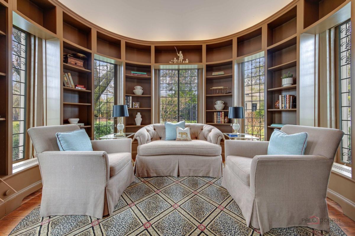 Sitting area with a couch, chairs, glass windows and large glass windows.