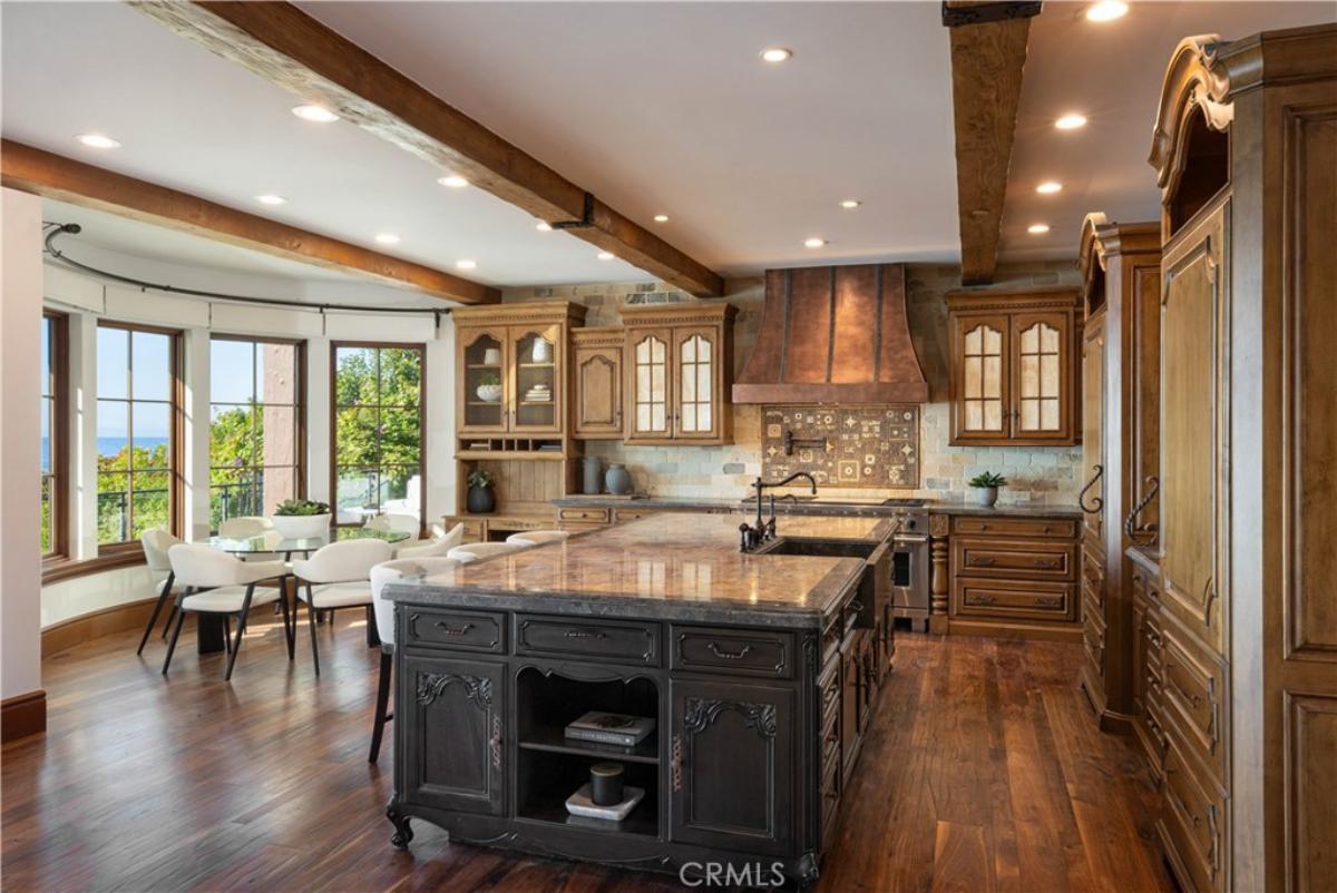 Kitchen with a large island, wooden floor, custom lights and custom cabinets.