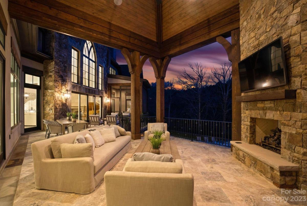Outdoor living area with a couch, TV and a fireplace.