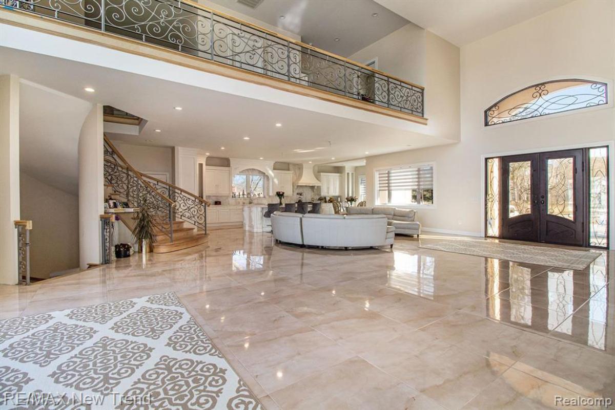 Foyer with a staircase, glass doors and a marble flooring.