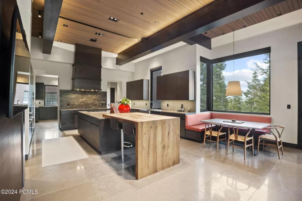 Kitchen with a large island, breakfast nook, glass windows and an open beam ceiling.