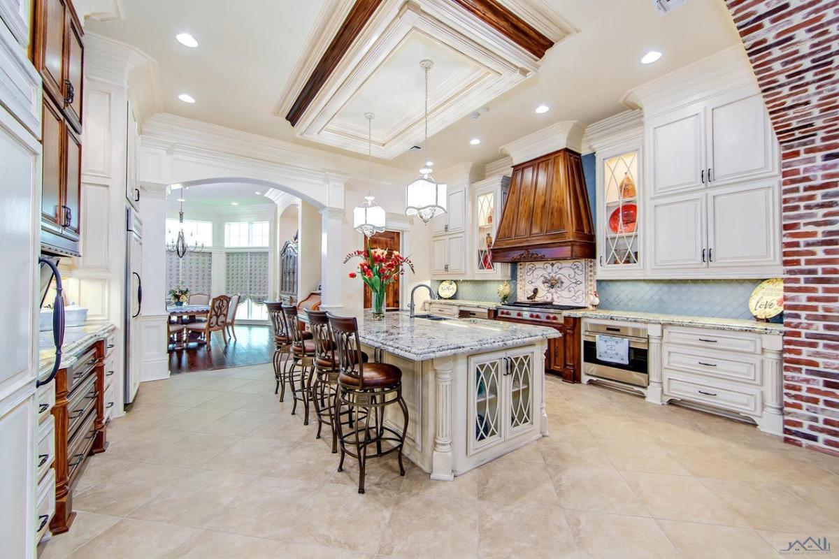 Kitchen with a large island, stove, custom lights and custom cabinets.