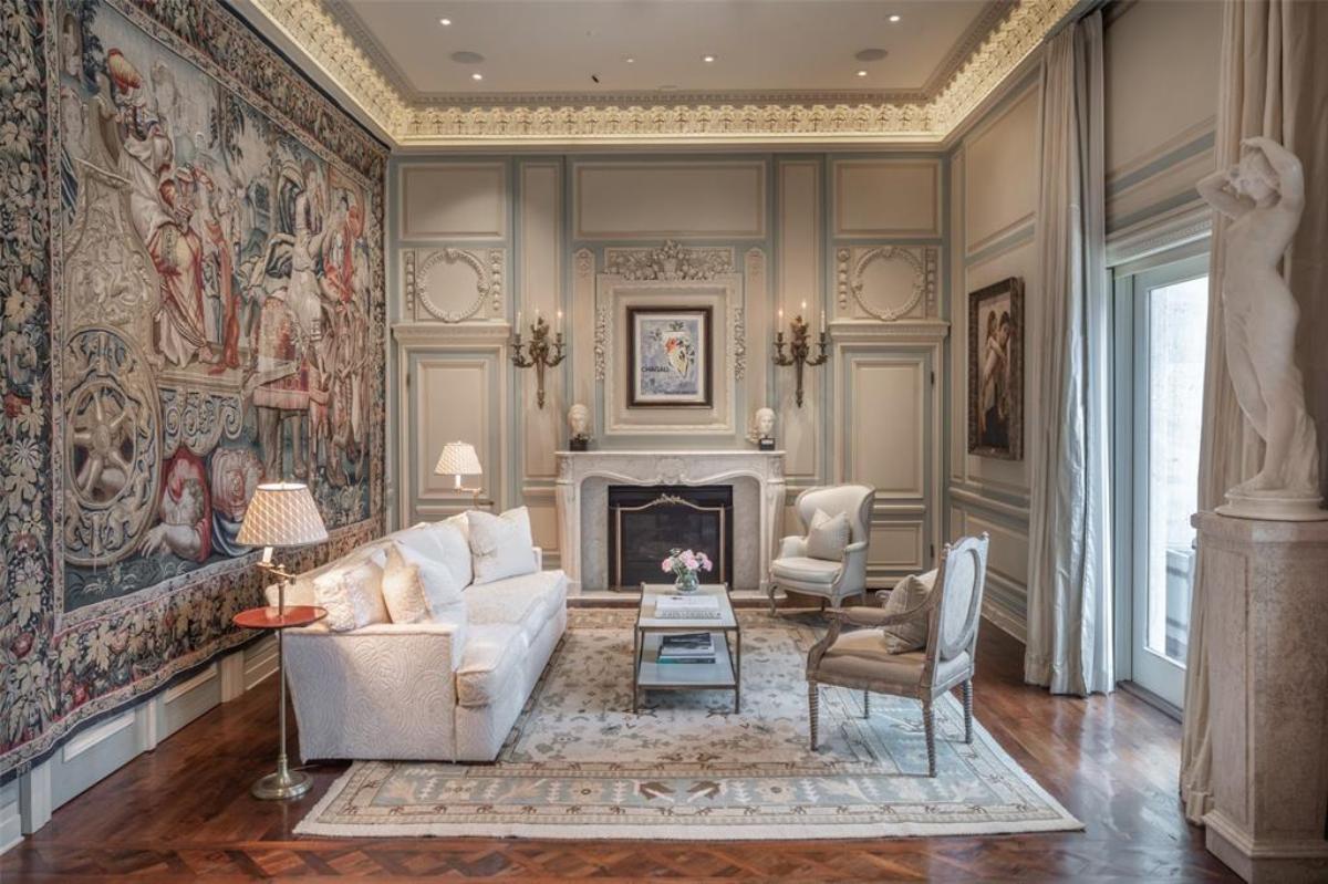 Sitting area with a couch, chairs, large rug and a fireplace.