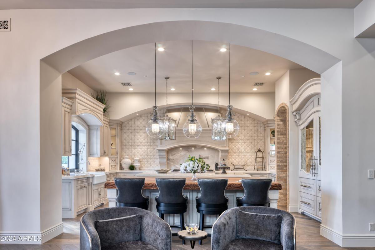 Kitchen with a large island, chairs and custom lights.