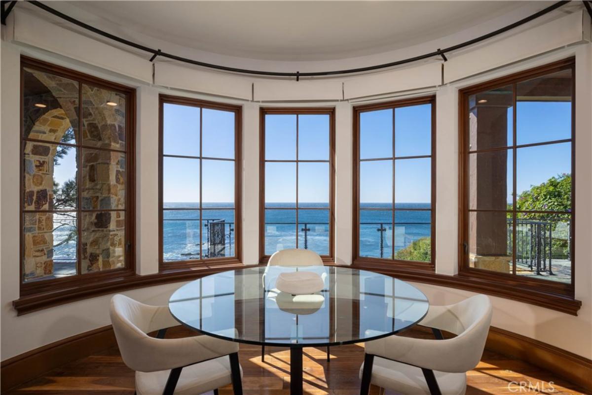 Breakfast nook with around table, chairs, glass windows overlooking the ocean.