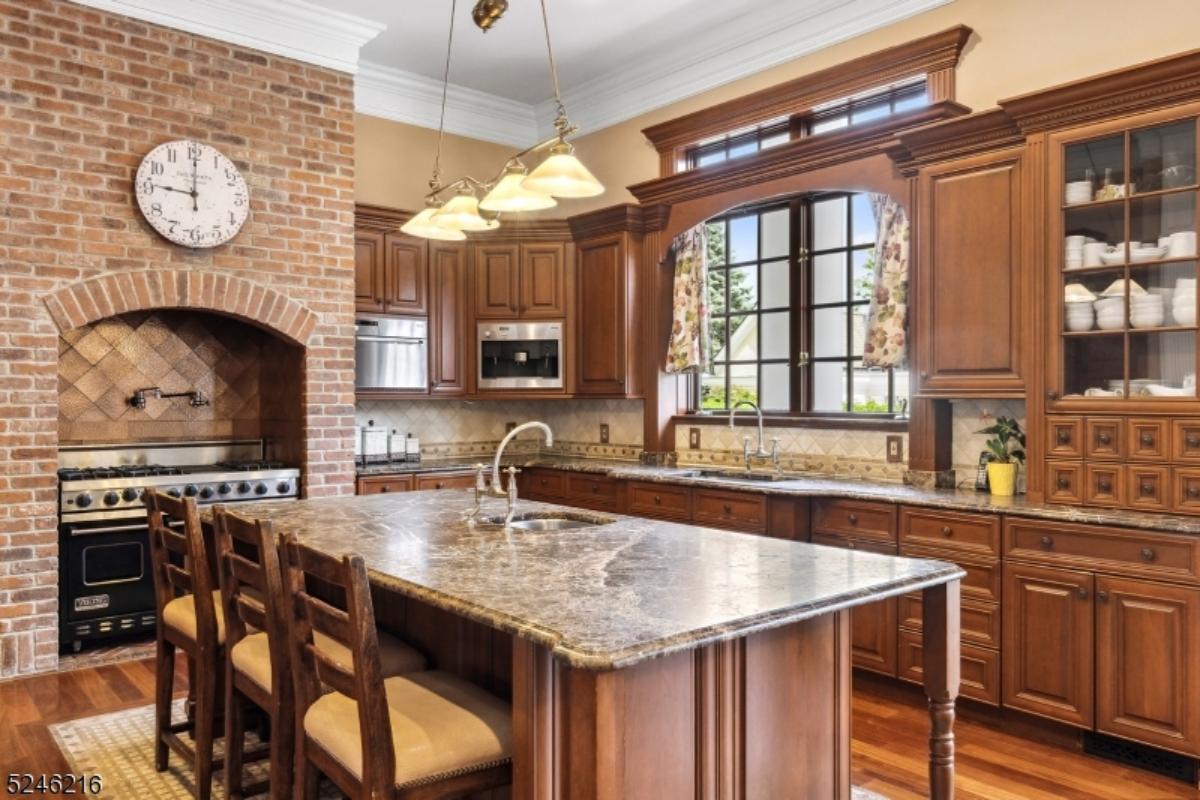 Kitchen with a large island, chandelier, wood flooring, and custom cabinets.