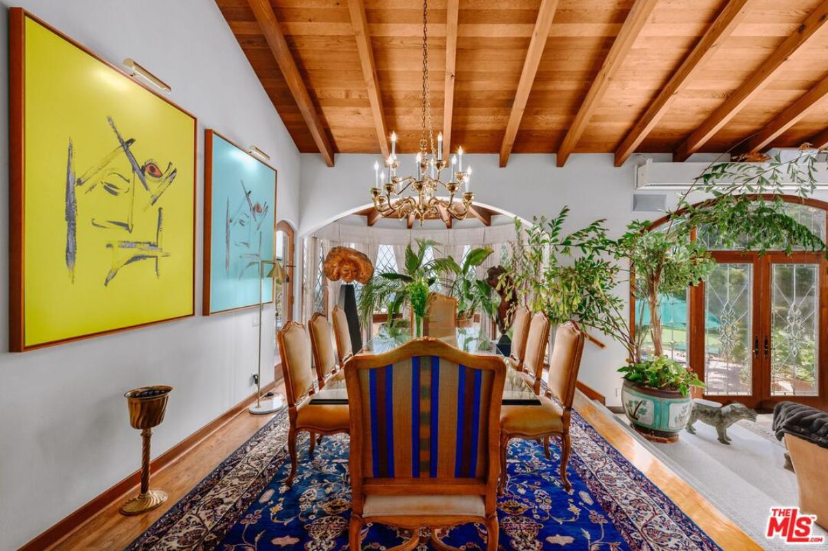 Dining room with a large table, chairs, chandelier, large rug and a wood flooring.