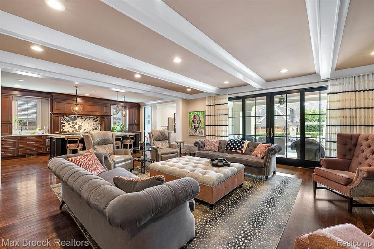 Living room with couches, glass door, glass windows and a large rug.