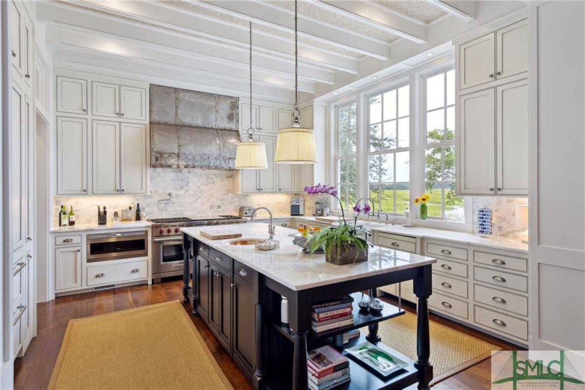 Kitchen with a large island, open beam ceiling and custom cabinetry.