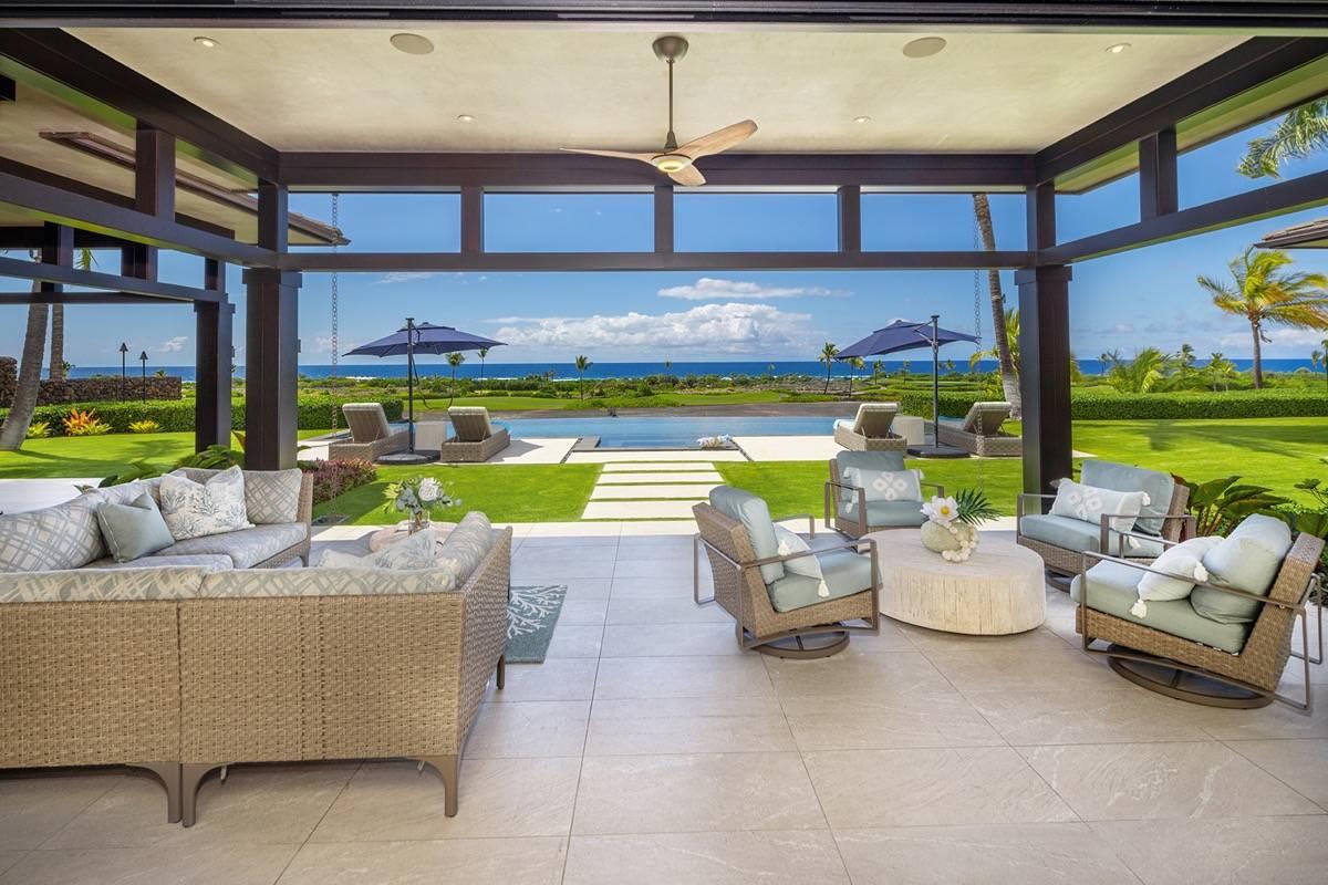 Covered patio with chairs, couch and tables next to the pool.