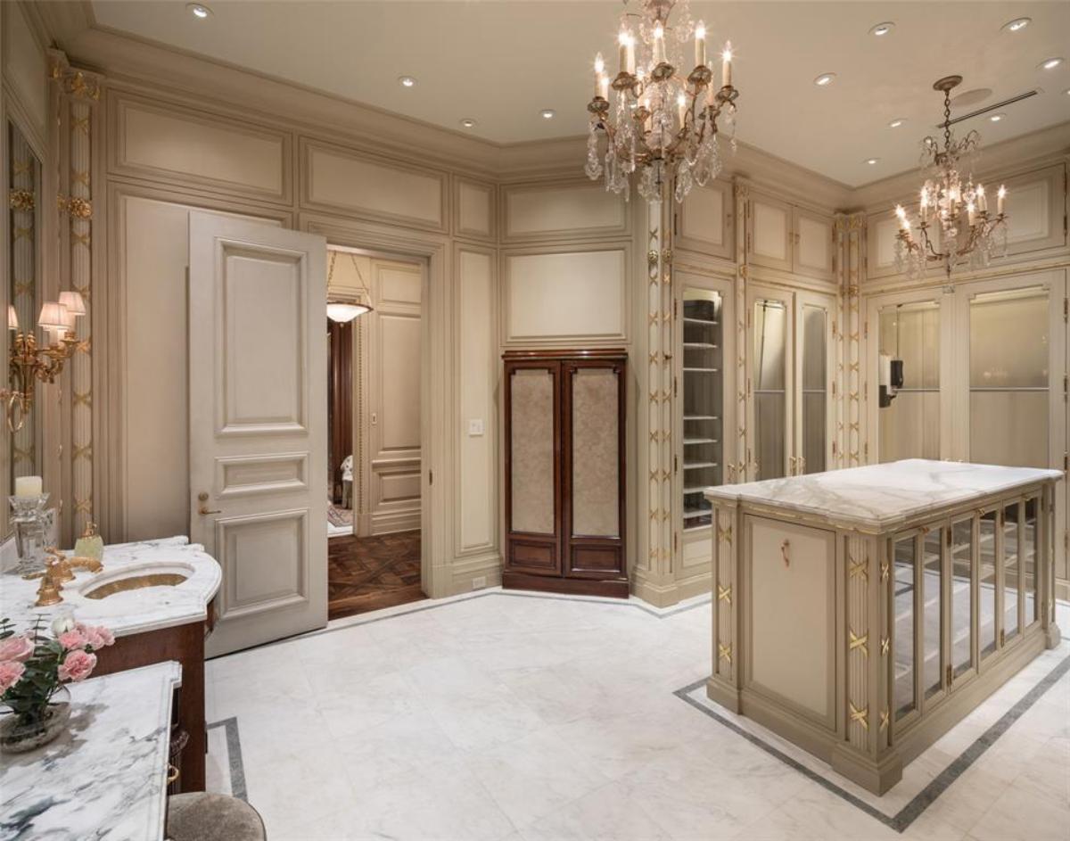 Walk-in closet with chandeliers, carpet flooring and marble counter top.