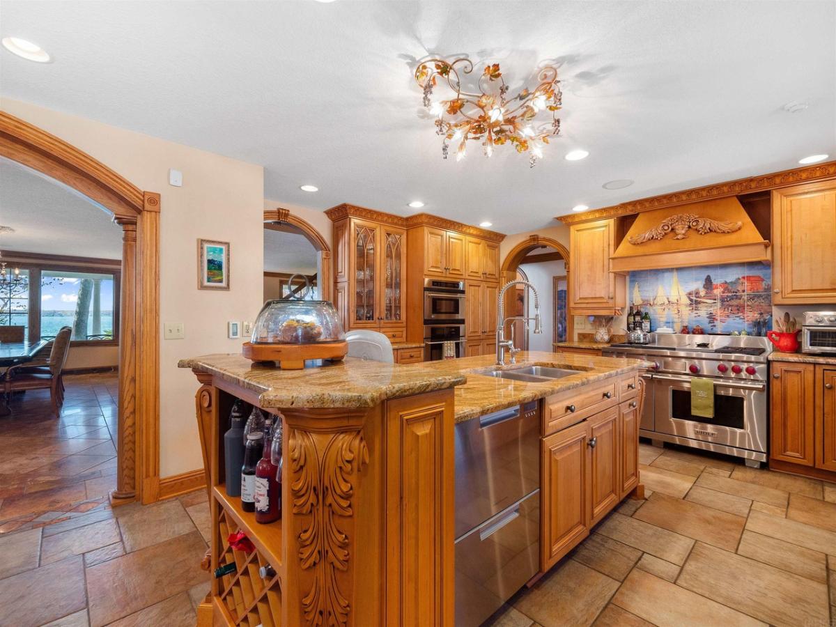 Kitchen with a large island, chandelier, stove and custom cabinets.