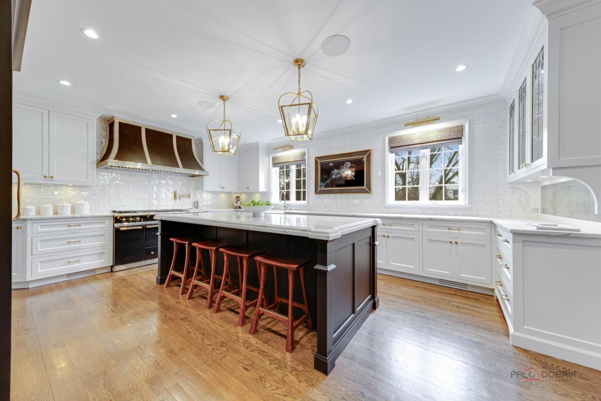 Kitchen with a large island, wood flooring, custom lights and custom cabinets.