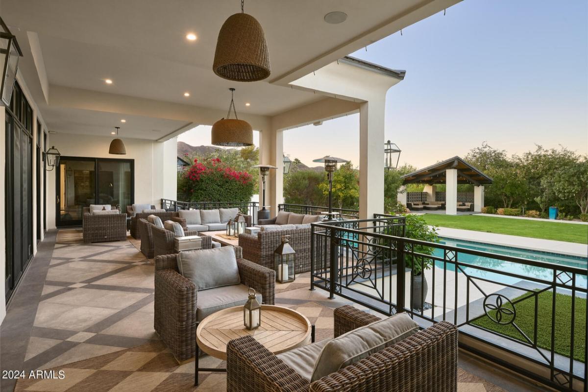Covered patio with chairs, couches and custom lights.