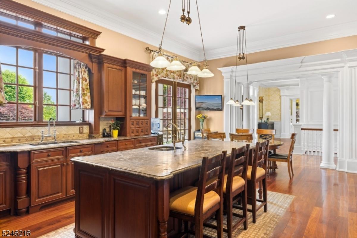 Kitchen with a large island, chandelier, wood flooring, and custom cabinets.