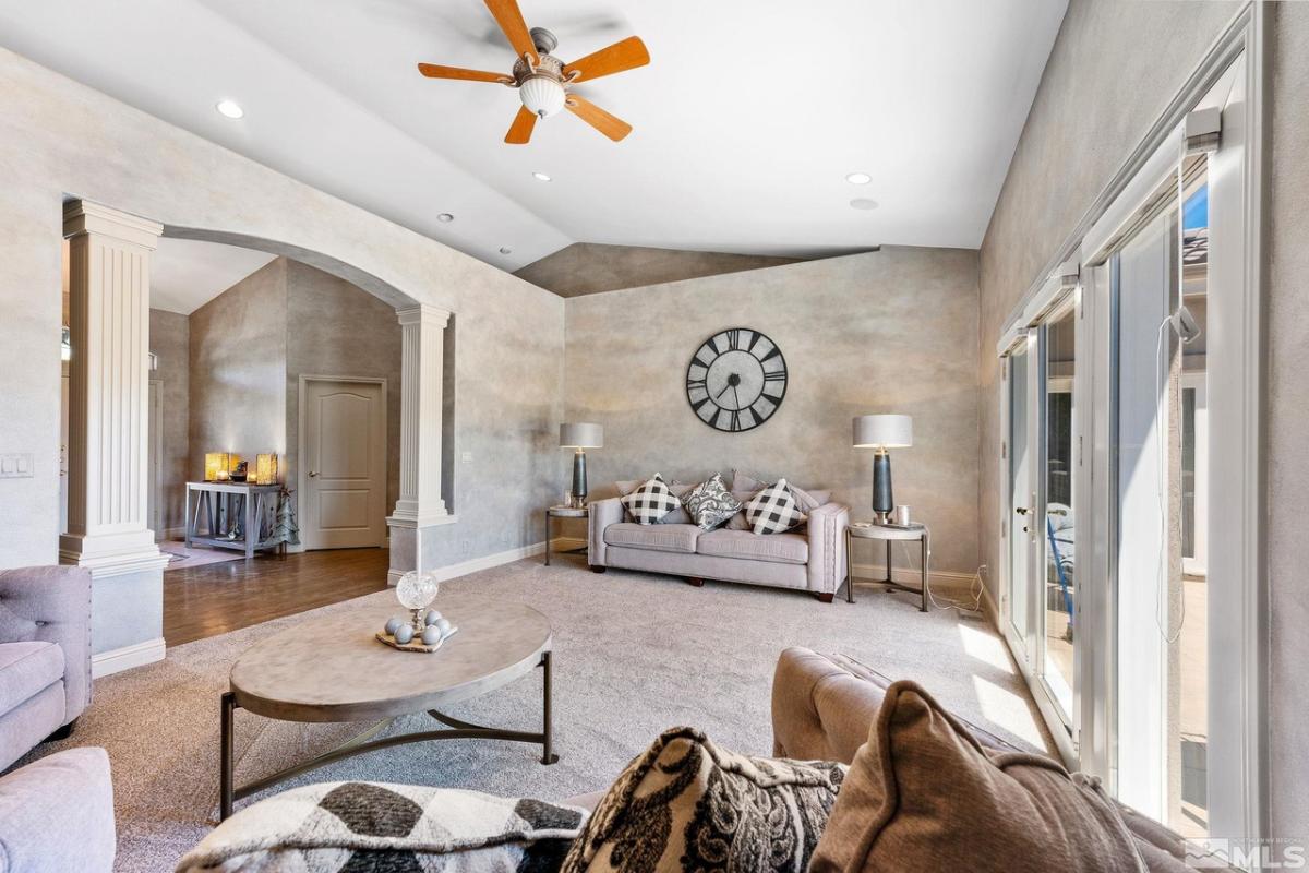 Living room with couches, glass doors and a carpet flooring.