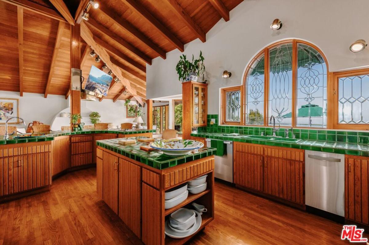 Kitchen with a large island, wood flooring, glass windows and wood ceiling.