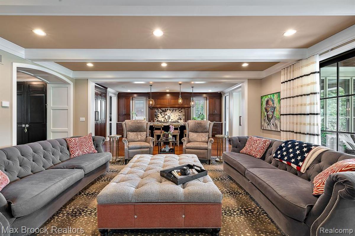 Living room with couches, glass door, glass windows and a large rug.