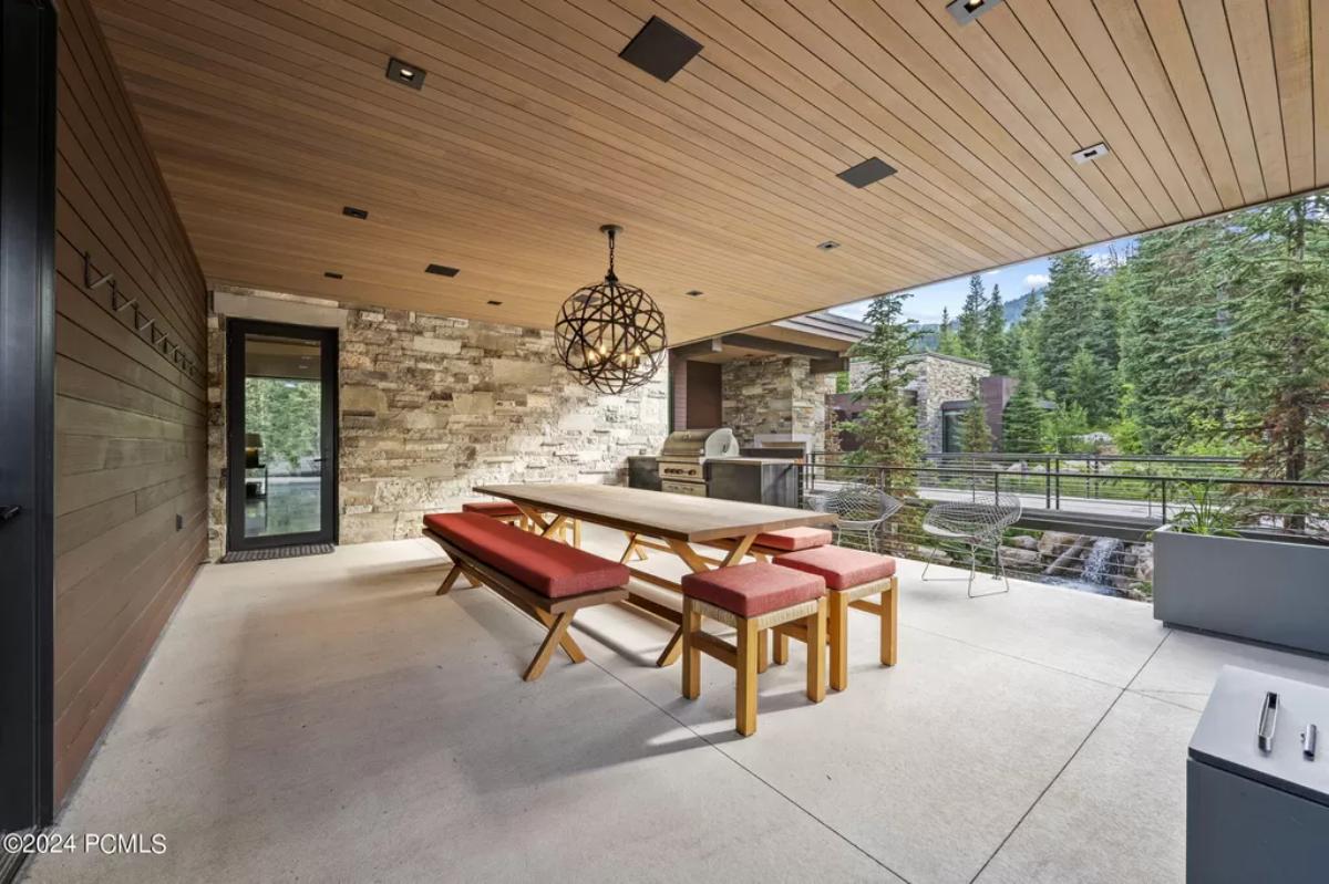 Outdoor dining area with a large table, chairs, and a grill area.