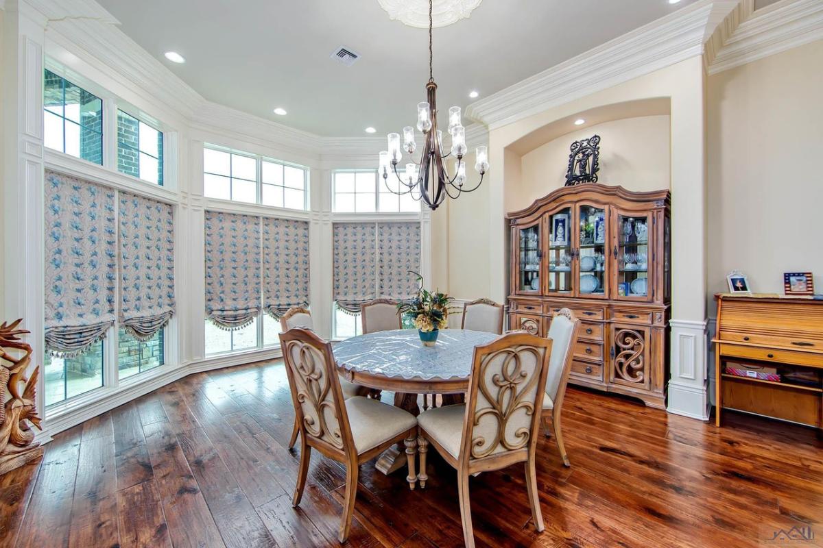 Breakfast nook with a round table, chairs, chandelier and a wooden floor.