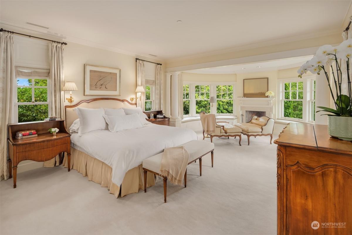 Bedroom with carpet flooring, fireplace and glass windows.