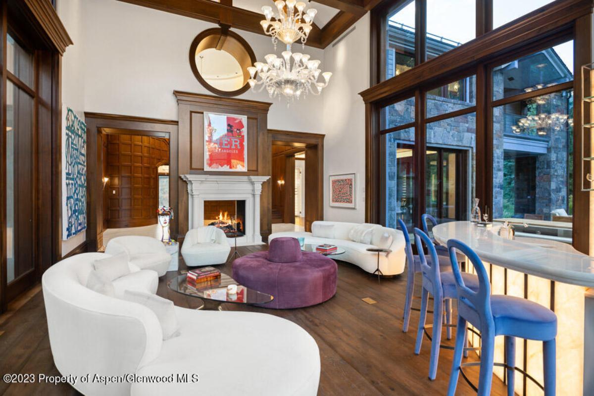 Living room with couches, glass walls, fireplace and a wooden floor.