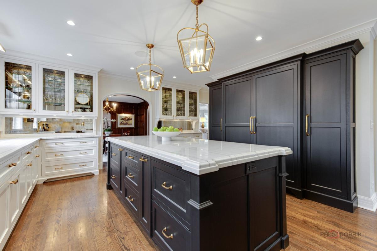 Kitchen with a large island, wood flooring, custom lights and custom cabinets.